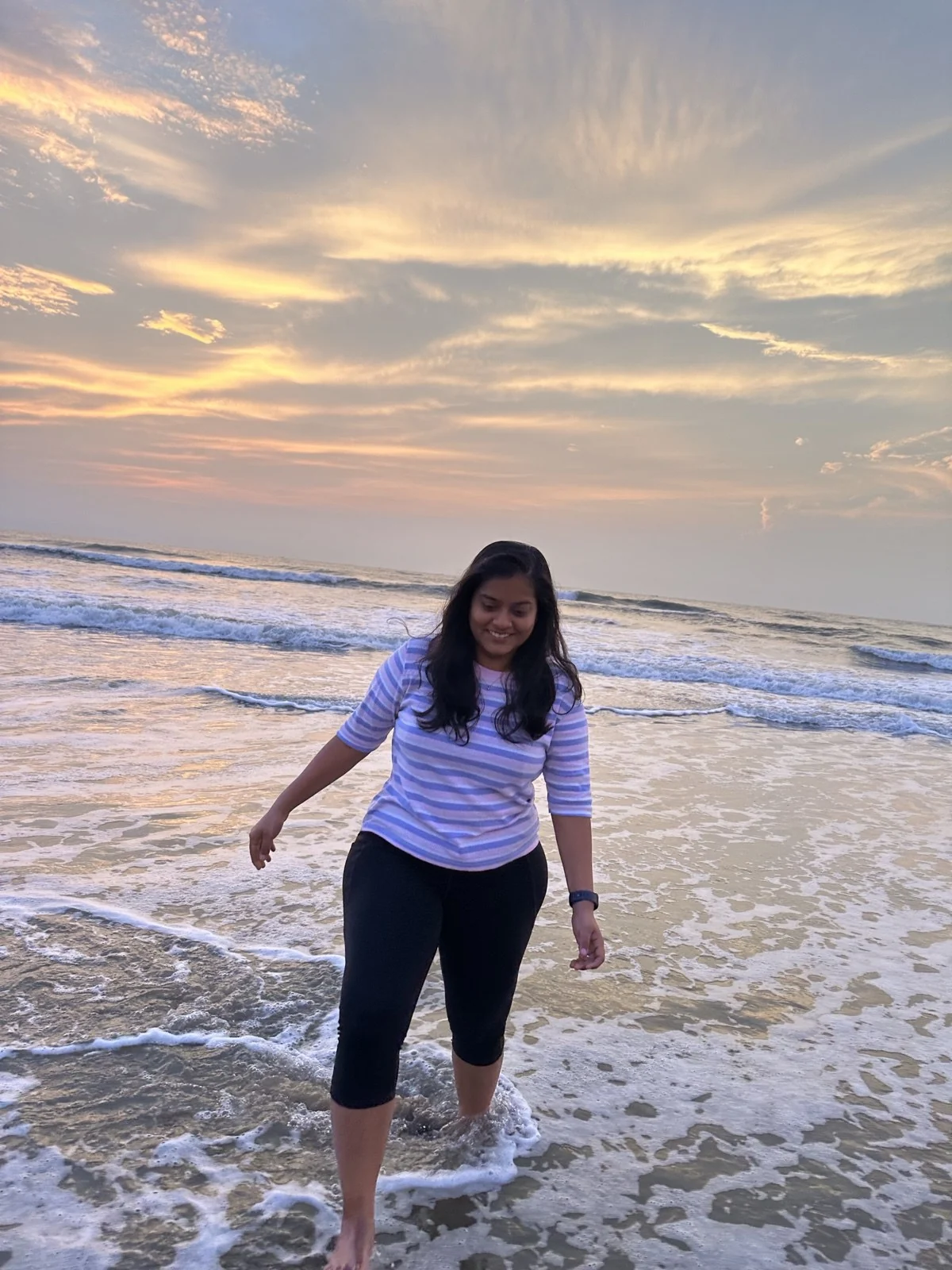 Premika walking through the waves at sunset.