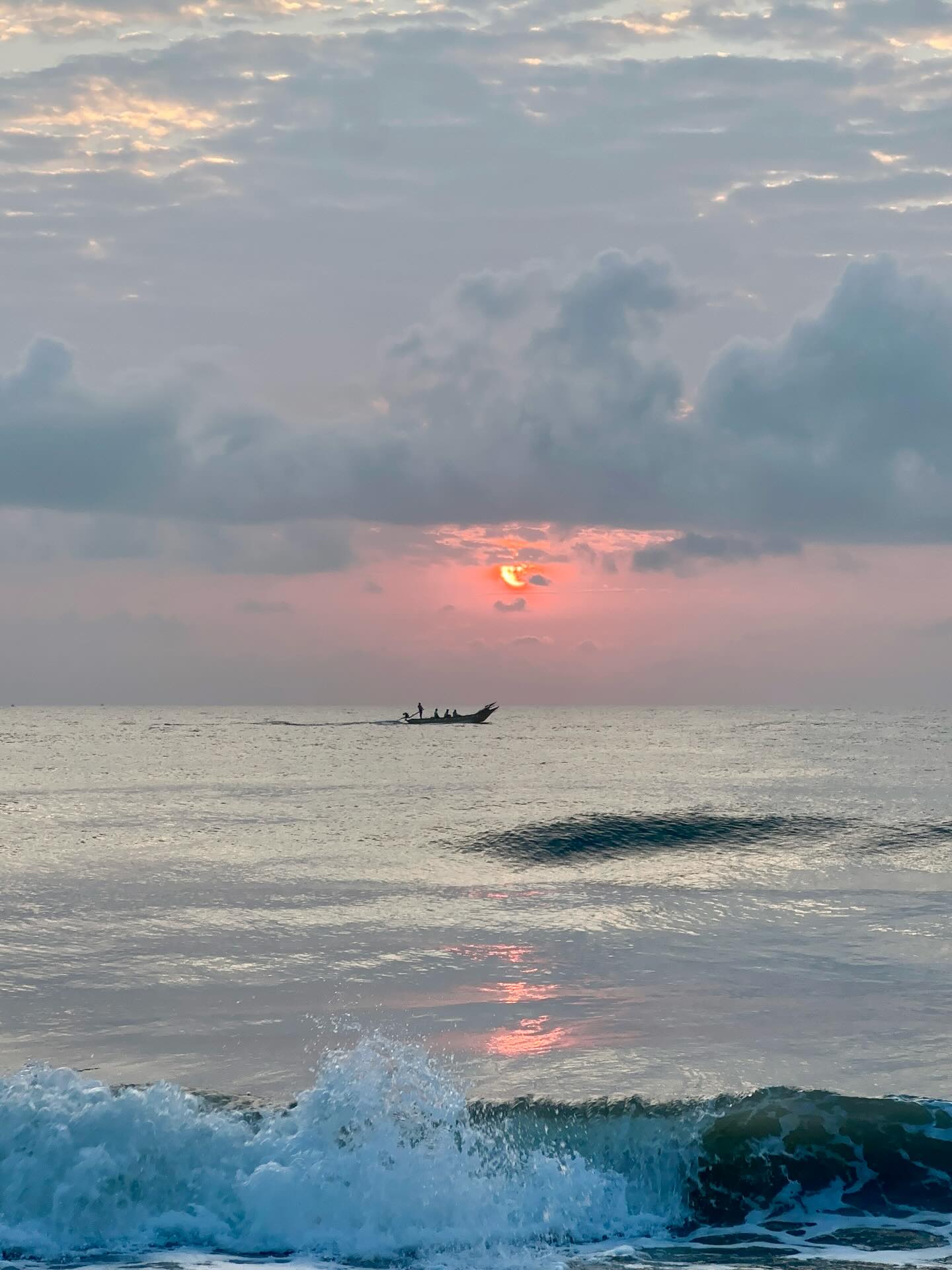 A low sun glowing through clouds above the sea.