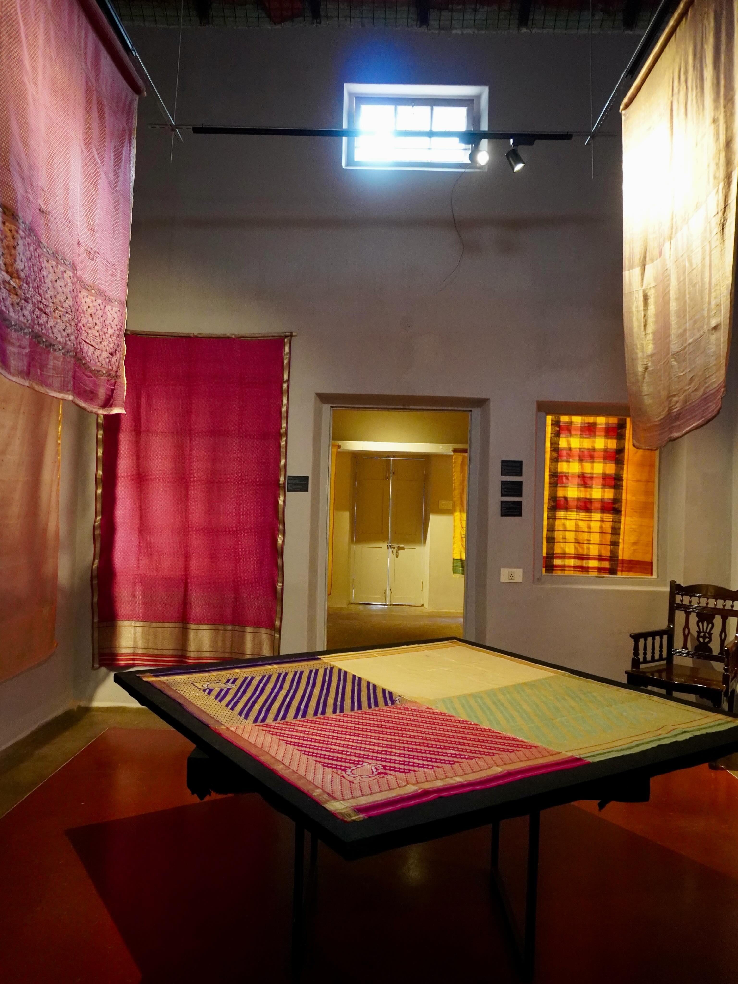 Warm light and colorful curtains around a patterned table in a quiet room.